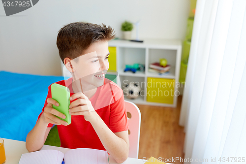 Image of student boy with smartphone distracting from study