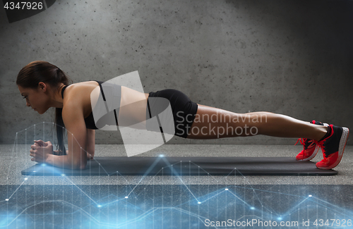 Image of woman doing plank exercise on mat in gym