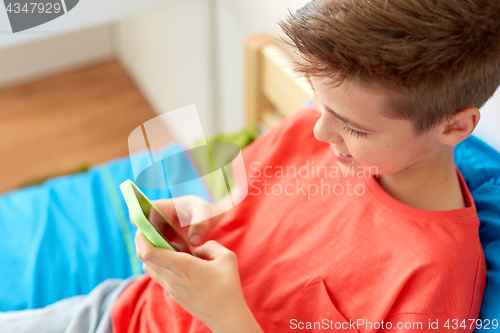 Image of close up of happy boy with smartphone at home