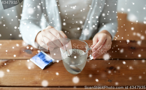 Image of ill woman stirring medication in cup with spoon