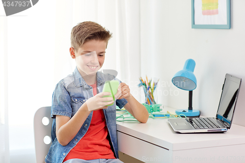 Image of happy boy with smartphone and laptop at home