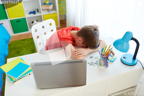 Image of tired or sad student boy with laptop at home