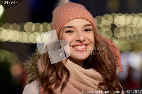 Image of happy young woman over christmas lights in winter