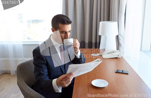 Image of businessman reading newspaper and drinking coffee