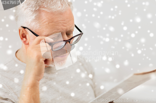 Image of close up of old man in glasses reading newspaper