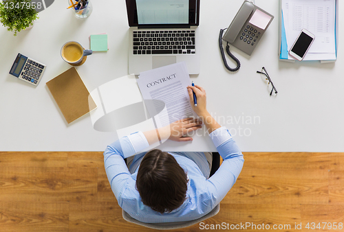 Image of businesswoman signing contract document at office