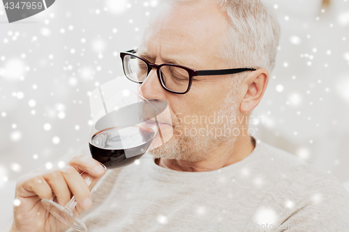 Image of senior man drinking red wine from glass