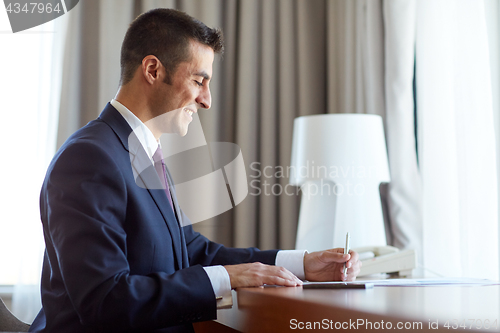 Image of businessman with papers working at hotel room