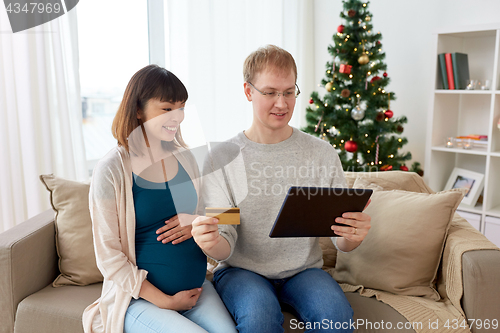 Image of man and pregnant wife shopping online at christmas