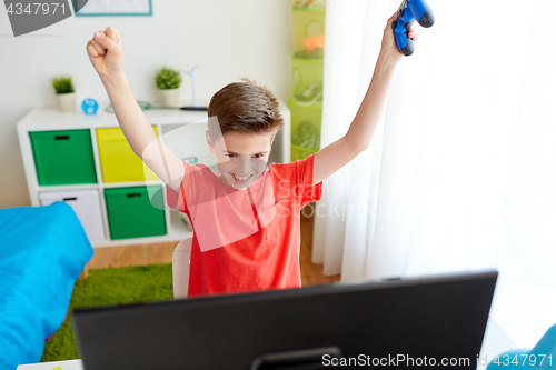 Image of boy with gamepad playing video game on computer