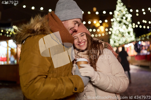 Image of happy young couple with coffee at christmas market