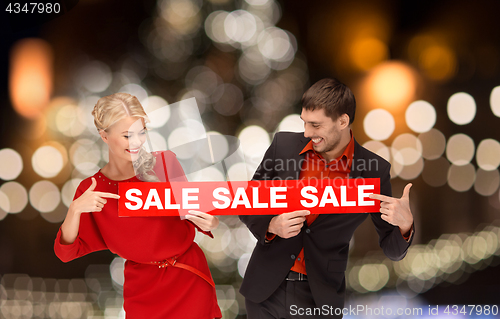 Image of couple with red sale sign over christmas lights