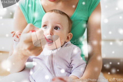 Image of mother with spoon feeding little baby at home