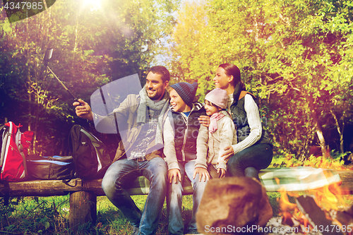 Image of family with smartphone taking selfie near campfire