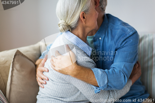 Image of close up of happy senior couple hugging at home