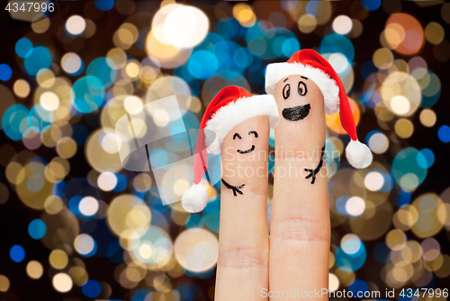 Image of two fingers in santa hats over christmas lights