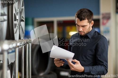 Image of auto business owner and wheel rims at car service