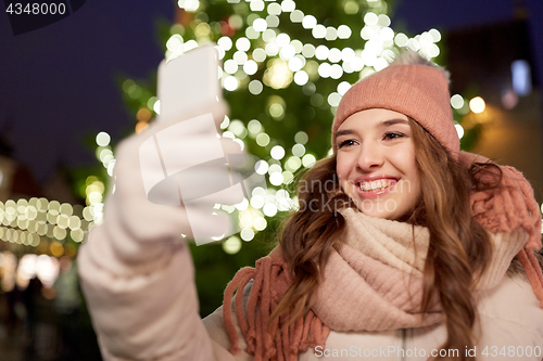 Image of young woman taking selfie over christmas tree