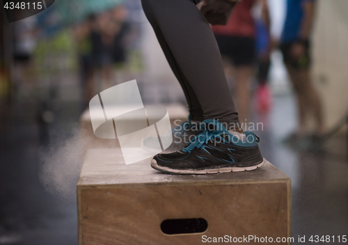 Image of black woman is performing box jumps at gym