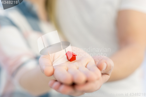Image of couple showing small red house in hands