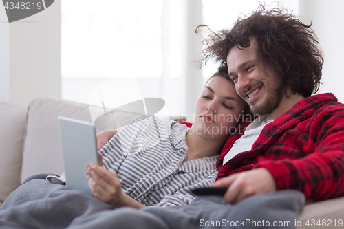 Image of couple relaxing at  home with tablet computers