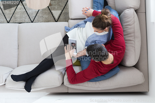 Image of couple relaxing at  home with tablet computers