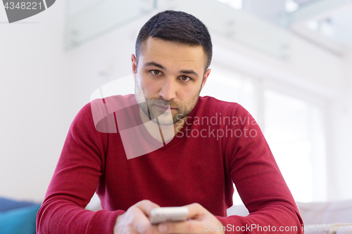 Image of young man using a mobile phone  at home