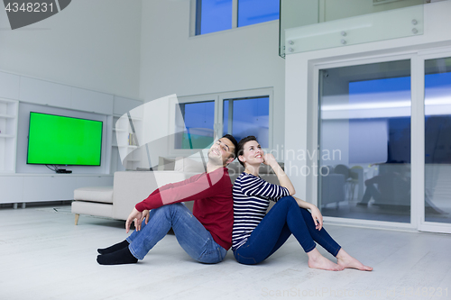 Image of young couple sitting with back to each other on floor