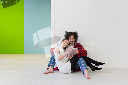 Image of Young Couple using digital tablet on the floor