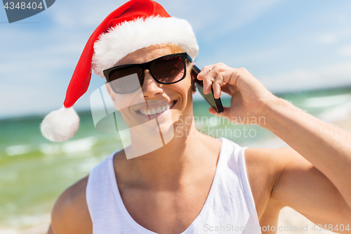 Image of man calling on smartphone on beach at christmas