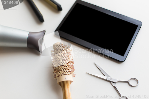 Image of tablet pc, scissors, hairdryer, hot iron and brush