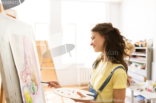 Image of student girl with easel painting at art school