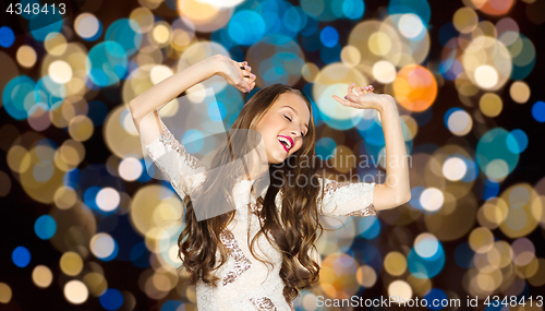 Image of happy young woman dancing over party lights