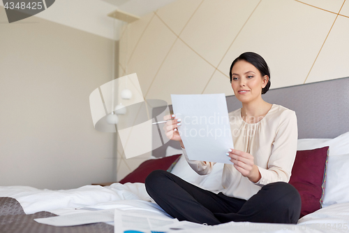 Image of businesswoman with papers working at hotel room