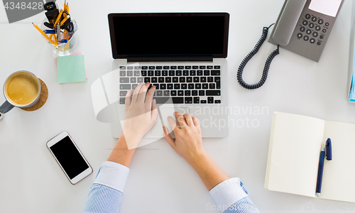 Image of hands of businesswoman working on laptop at office