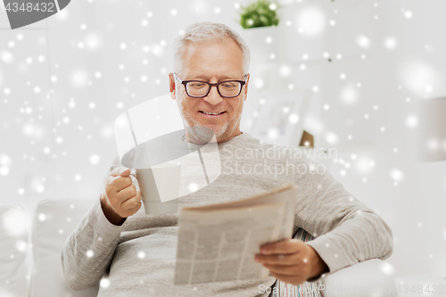 Image of senior man in glasses reading newspaper at home