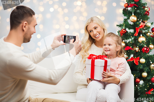 Image of man photographing his family with christmas gift