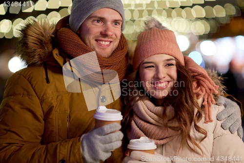 Image of happy couple with coffee over christmas lights