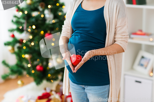 Image of close up of pregnant woman with heart at christmas