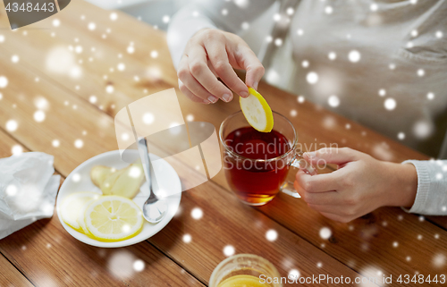 Image of close up of woman adding honey to tea with lemon