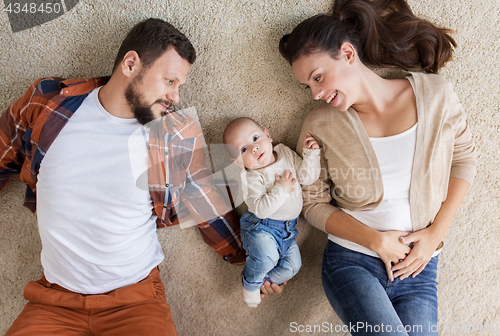 Image of happy family with baby lying on floor at home