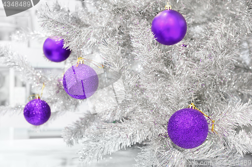 Image of baubles ultraviolet on silver artificial Christmas tree