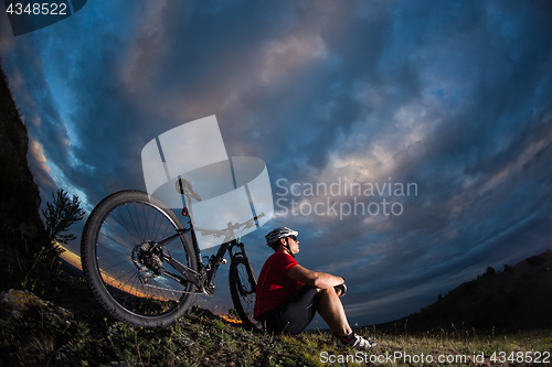 Image of guy has a rest sitting near his bike