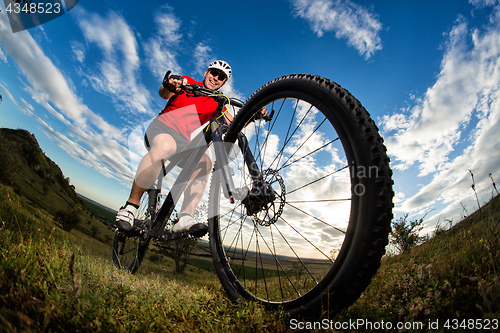 Image of cyclist riding mountain bike on rocky trail at sunrise