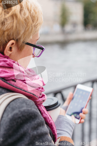 Image of Woman using smartphone at river