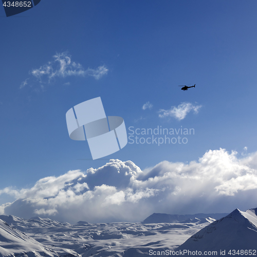 Image of Helicopter above snowy plateau and sunny sky