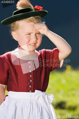 Image of Little girl in a dress looks in the country