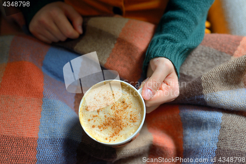 Image of Woman holding hot cup of cappuccino