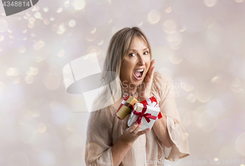 Image of Surprised woman holding some Christmas gifts