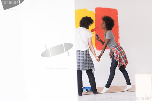 Image of multiethnic couple painting interior wall